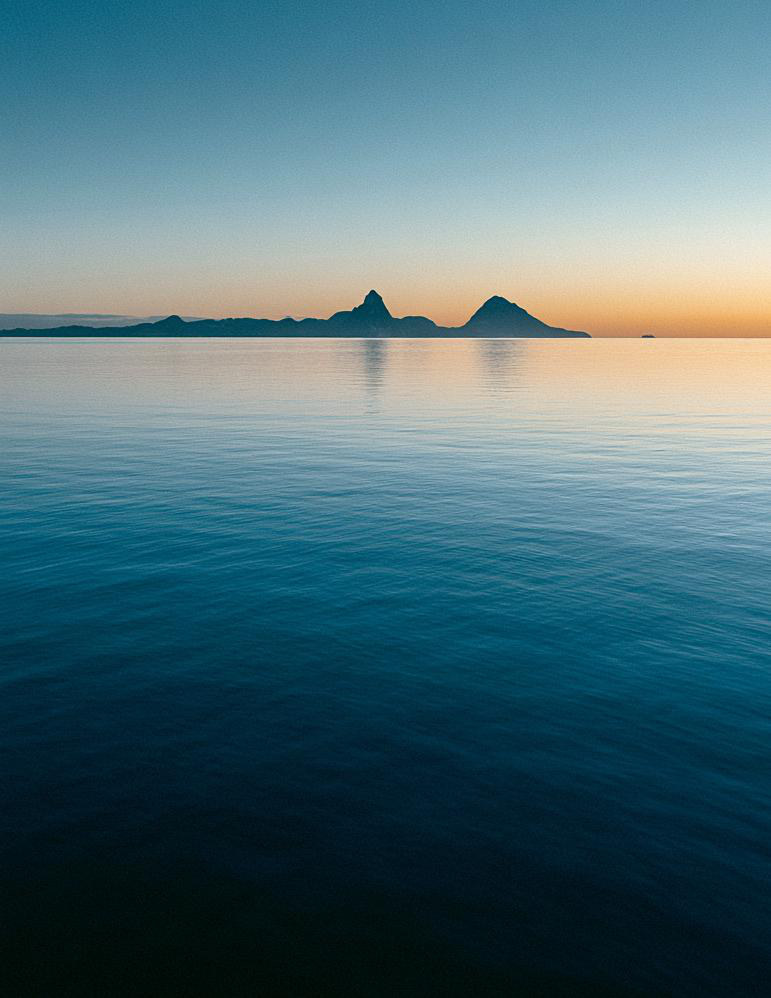 First light over a calm sea, the island low on the horizon.