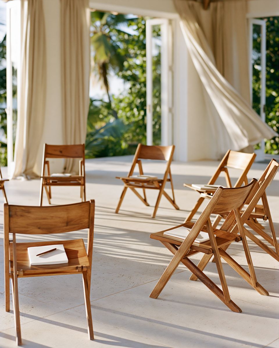 A circle of empty wooden chairs with notebooks, in daylight.