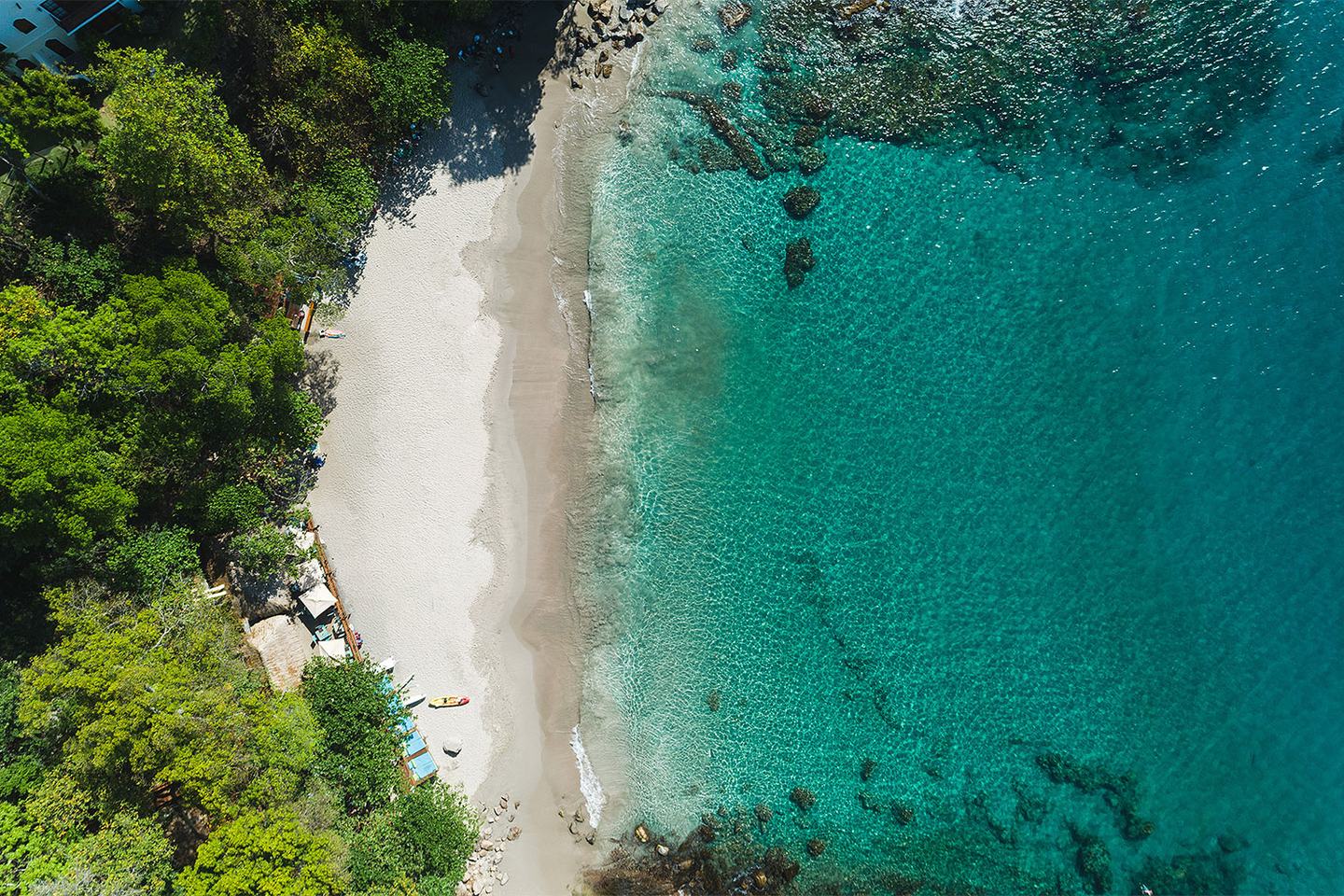 Beach meeting clear turquoise shallows below Cap Maison, seen from above.